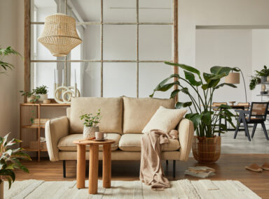 Modern living room interior composition with beige sofa, wooden coffee table and modern home accessories. Template. Copy space. Dining room in the background.
